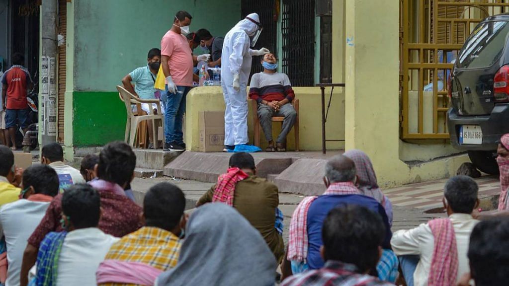 Medics take samples for Covid-19 swab tests as people wait for their turn at a containment zone, during the ongoing nationwide lockdown to curb the spread of coronavirus, in Guwahati, on 18 May 18 | PTI