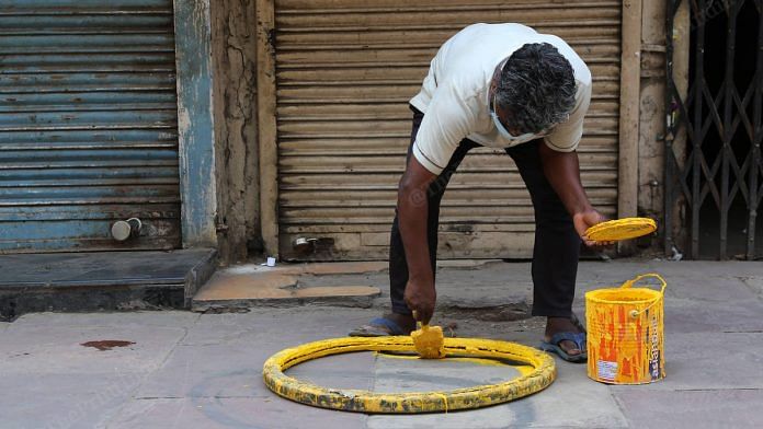 A worker paints a social distancing circle outside a liquor store in Daryaganj | Photo: Manisha Mondal | ThePrint