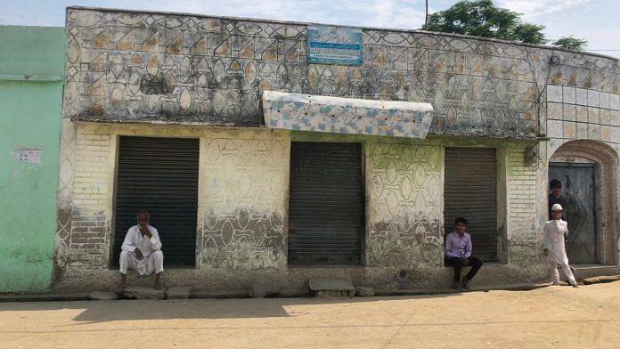 People sit outside shuttered shops on an empty street in Rampur district, UP | Jyoti Yadav | ThePrint