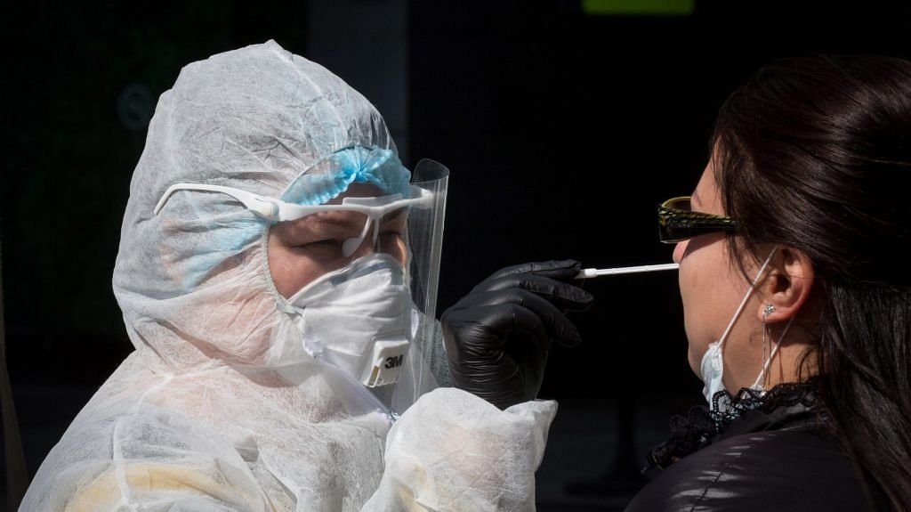 A medical worker dressed in personal protective equipment (PPE) takes a nasopharyngeal swab sample from a visitor at a Chaika Clinic mobile covid-19 sample-collection site in Moscow International Business Center (MIBC) | Photographer: Andrey Rudakov | Bloomberg