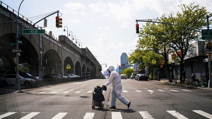 A man wearing a protective suit crosses a street in Queens, New York City on May 15 | Representational image | Bloomberg