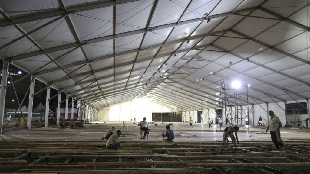 Workers lay flooring panels during the construction of a 1000 bed hospital for Covid-19 treatment at the Bandra Kurla Complex at night in Mumbai | Bloomberg