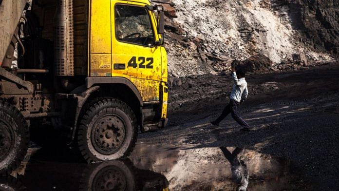A worker is reflected in a puddle as he walks towards a truck at an open cast coal mine in Bastacolla Colliery in Jharia, Jharkhand | Photographer: Sanjit Das | Bloomberg photo