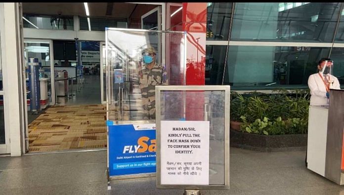 CISF personnel stand behind a glass shield near the gates at IGI Airport's Departures section | Revathi Krishnan | ThePrint