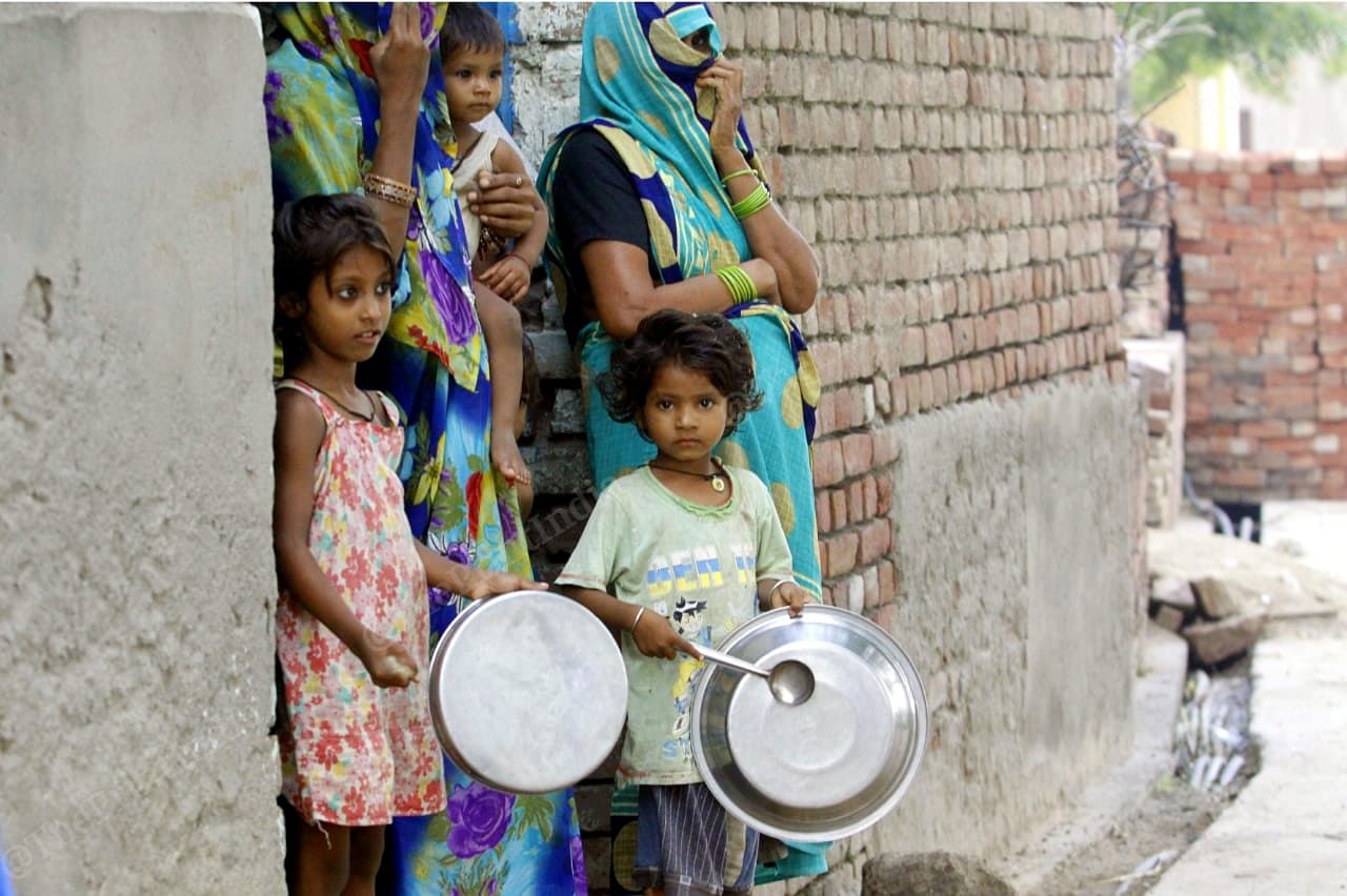 Young children with their mothers stand outside their homes, Nearly every child could be seen armed with a utensil and spoon, ready to start making clanging noises | Praveen Jain | ThePrint