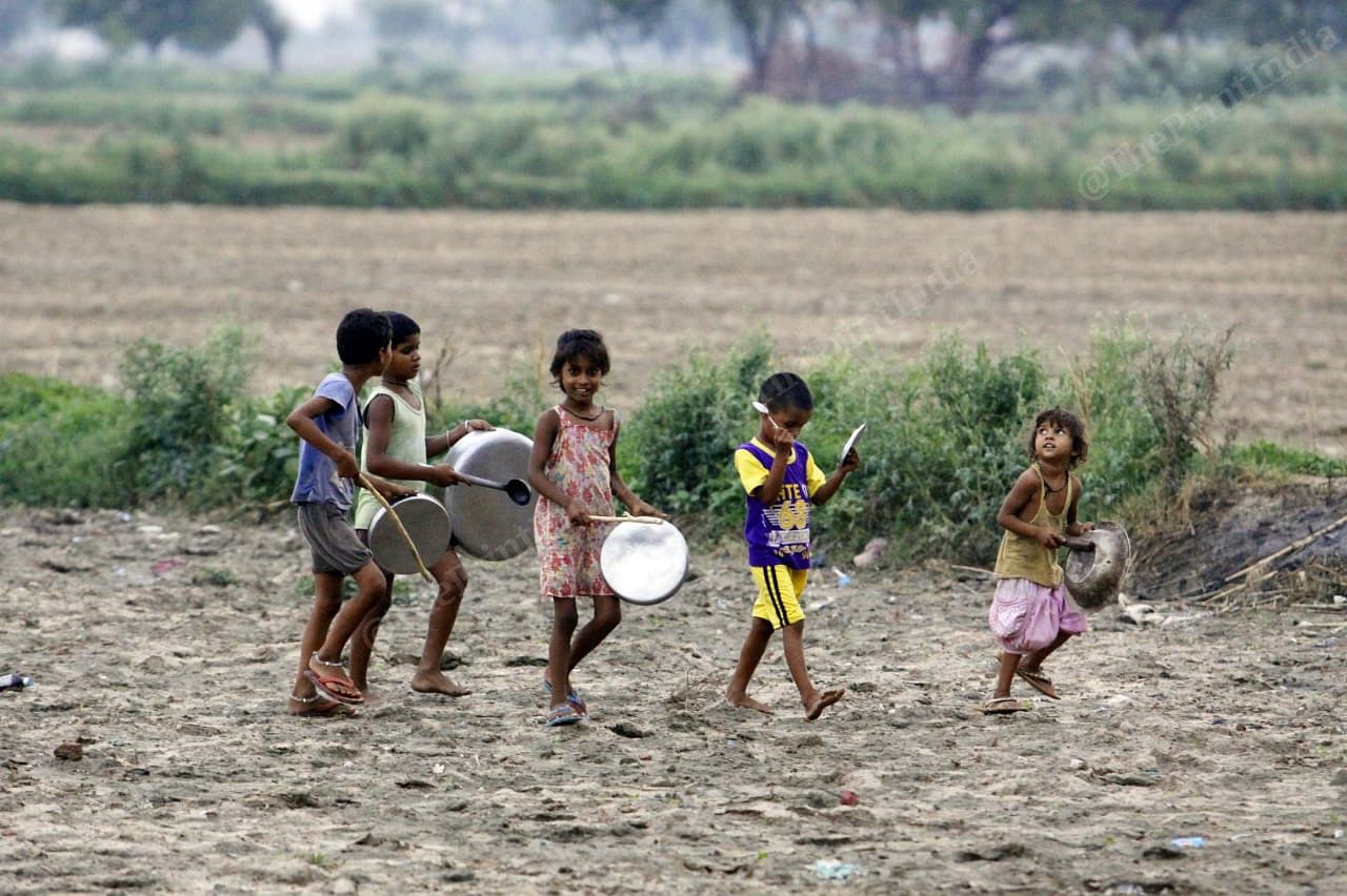 Looking up at the swarm of locusts in the sky, young children in Baghai village go to the fields clanging utensils to ensure that the locusts don’t eat their crops. It is believed the noise scares the pests away | Praveen Jain | ThePrint