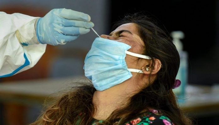 A medic takes swab samples for Covid-19 infection from a woman at a testing centre inside a government school in New Delhi. | PTI