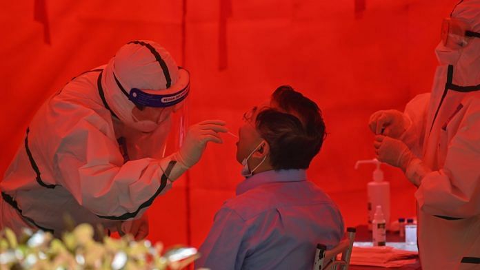 A medical worker takes a swab sample from a man to test for coronavirus in Wuhan, May 19. | Photographer: Hector Retamal | Bloomberg AFP via Getty Images
