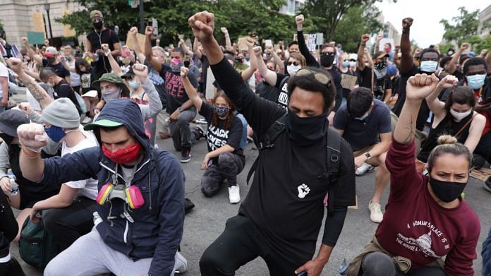 Demonstrators kneel and raise their fists during a protest against police brutality and the death of George Floyd, on June 2, 2020 in Washington, DC. | Photo by Alex Wong/Getty Images | Bloomberg