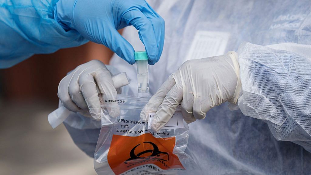 A medical worker drops a Covid-19 test sample into a plastic bag at a testing site in Berkeley, California, US | Photographer: David Paul Morris | Bloomberg