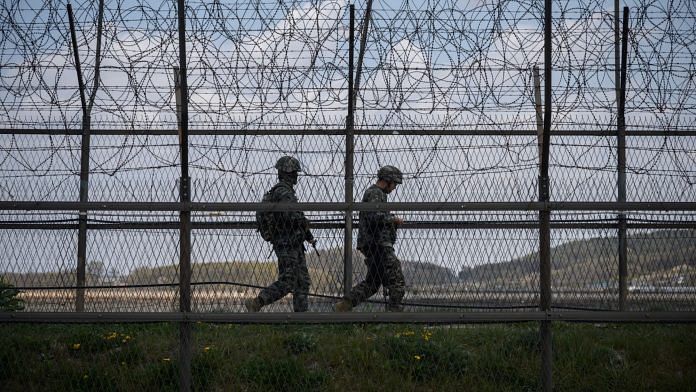 South Korean soldiers patrol along a barbed wire fence Demilitarized Zone (DMZ) separating North and South Korea, on the South Korean island of Ganghwa on April 23