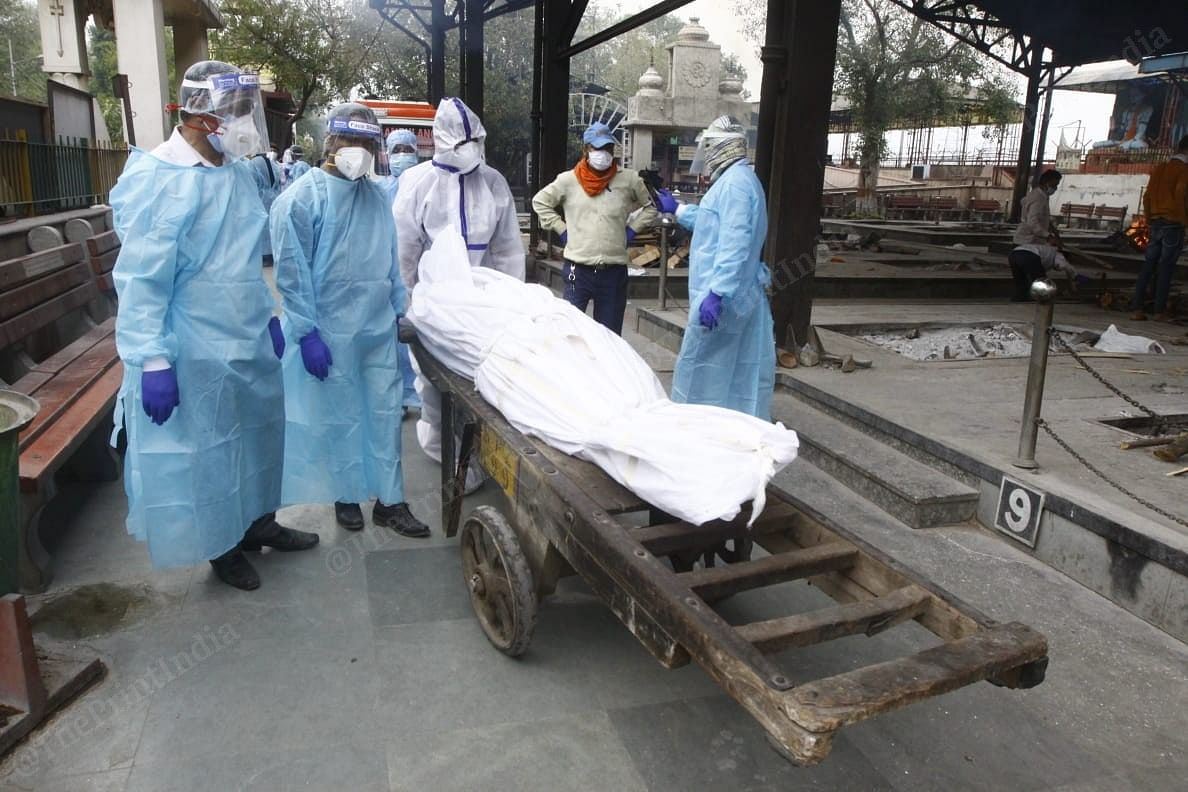 Hospital workers in PPE gear unload a Covid patient's body at Nigambodh Ghat | Praveen Jain | ThePrint