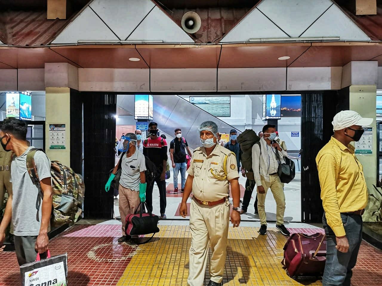 Scores of policemen at Guwahati Railway Station, ensure that social distancing is maintained between passengers while officials gather their details. They are then sent off to one of the five zonal screening facilities setup across the state. | Photo: Angana Chakrabarti | ThePrint