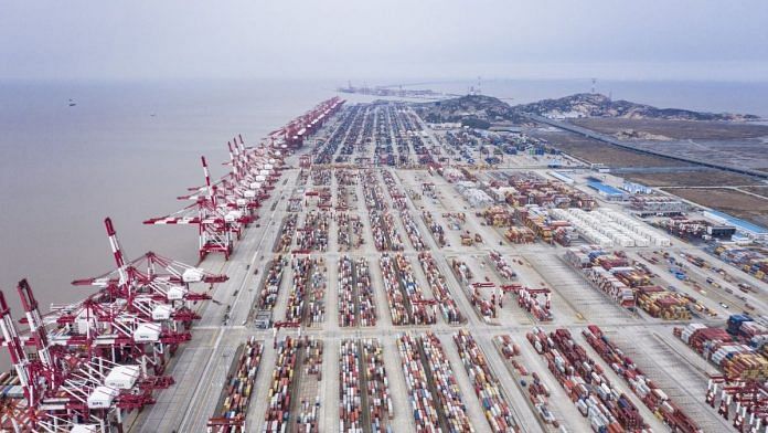 Shipping containers sit stacked next to gantry cranes at the Yangshan Deep Water Port | Bloomberg
