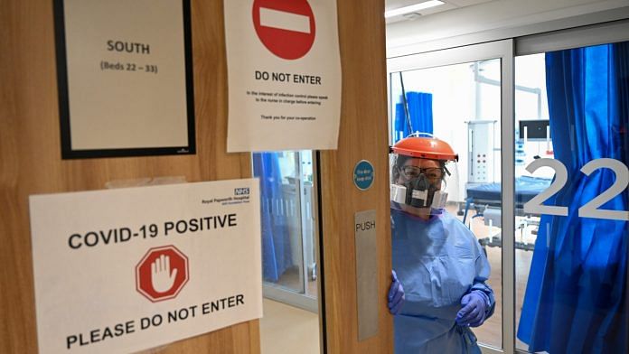 A medical worker in PPE suit holds the door, to a Covid-19 positive area, in the ICU at a hospital in Cambridge