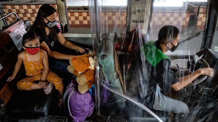 A driver sits behind a plastic covering for protection inside a bus on the first day of relaxed quarantine measures in Caloocan, Metro Manila, Philippines on 1 June