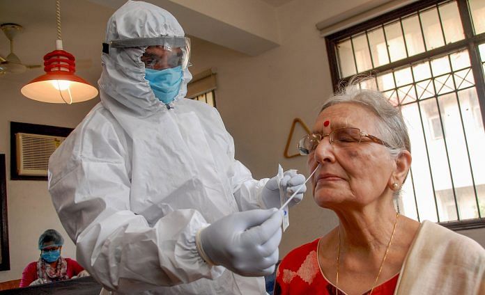 A medic collects a sample from a resident of Steller King Court society for Covid-19 test, in Noida, Friday, 17 July, 2020.| PTI