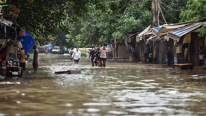 People wade across a flooded road following heavy rain in New Delhi on Sunday | PTI