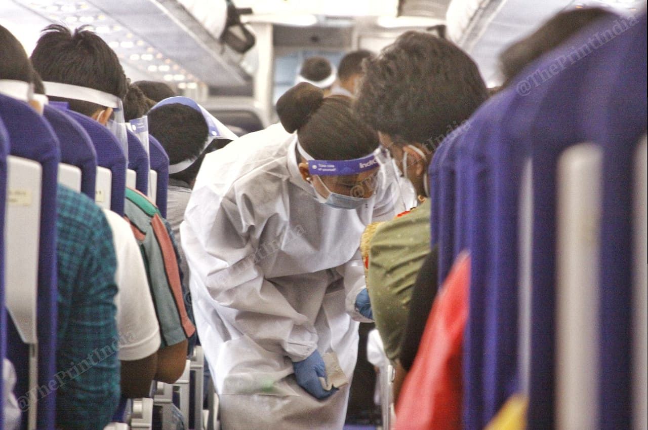 A flight attendant in a PPE kit gives safety advisories and instructions to passengers | Praveen Jain | ThePrint