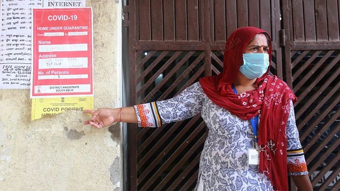 An ASHA worker, pastes a Covid-19 isolation poster outside a patient's house | Manisha Mondal | ThePrint