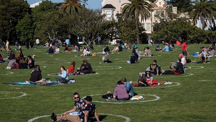 People lay on the grass in circles drawn to promote social distancing at Dolores Park in San Francisco, California, U.S., on Thursday, May 21, 2020. David Paul Morris | Bloomberg