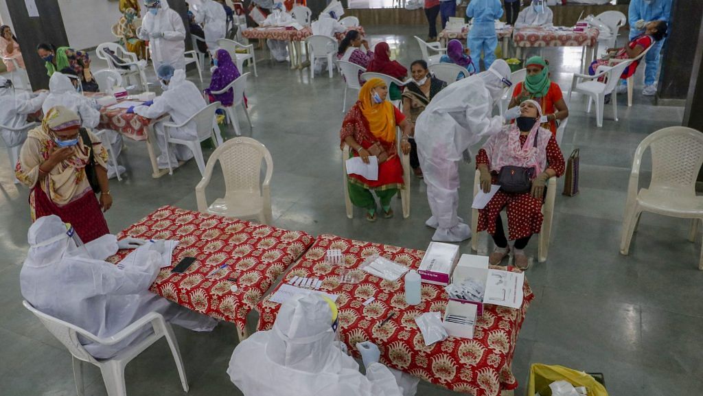Healthcare workers wearing personal protective equipment (PPE) kits collect swab samples of municipal school teachers for Covid-19 test, in Ahmedabad. | PTI