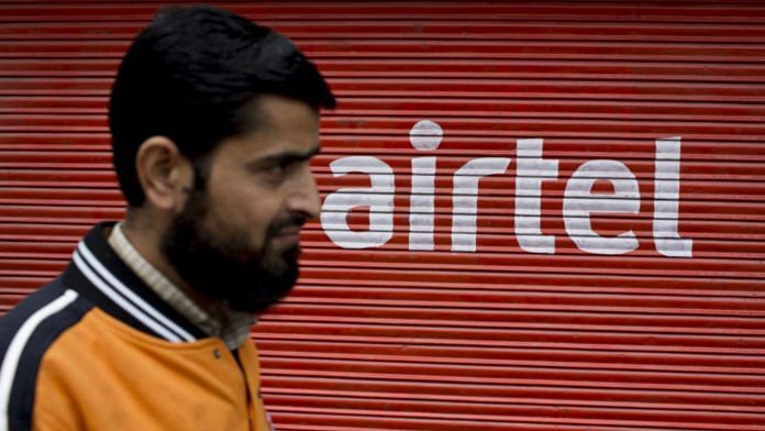 A man walks past a shutter of a closed store displaying the Bharti Airtel Ltd. logo. | Photographer: Brent Lewin | Bloomberg