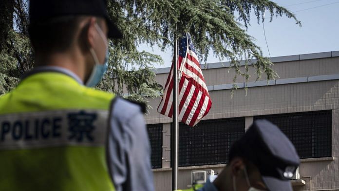 Police officers stand near an American flag flown in front of the US Consulate General Chengdu in Chengdu on 26 July.