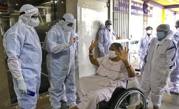 A woman waves goodbye to her doctors while getting discharged from the hospital after her recovery from Covid-19 | Photo: Praveen Jain | ThePrint