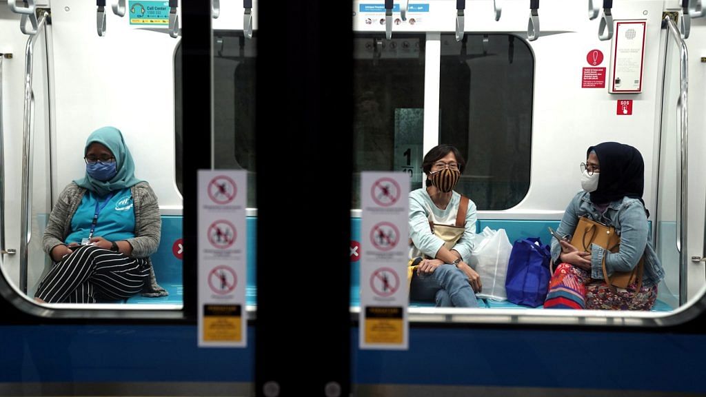 Passengers wearing protective face masks sit inside a train at a station in Jakarta on July 8