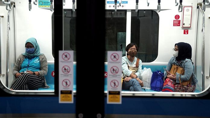 Passengers wearing protective face masks sit inside a train at a station in Jakarta on July 8