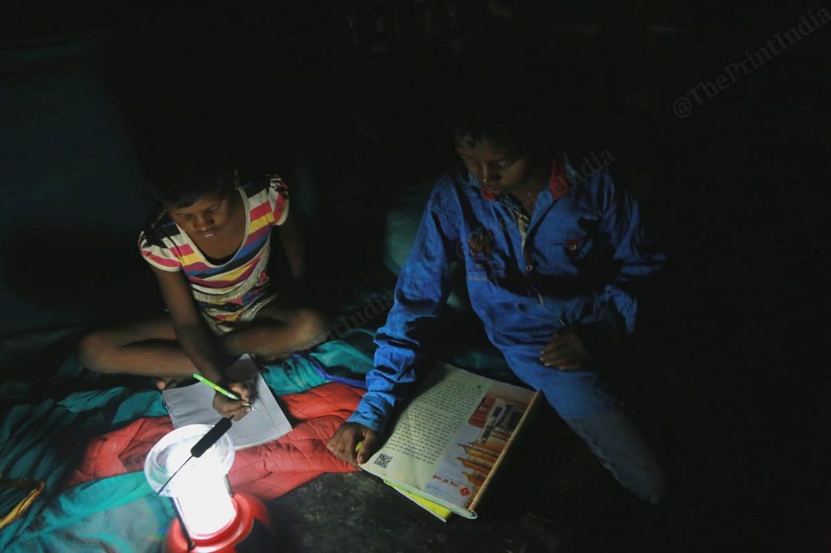 Children in the village use a night lamp to study. The night lamp is charged using a solar plate provided by a NGO| Photo: Manisha Mondal | ThePrint