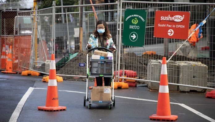 A pedestrian wearing a protective mask pushes a cart in Auckland, New Zealand due to Covid lockdown | Brendon O'Hagan/Bloomberg
