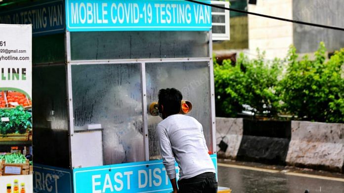 A health worker collects swab sample for coronavirus at a mobile testing van in New Delhi | Suraj Singh Bisht | ThePrint