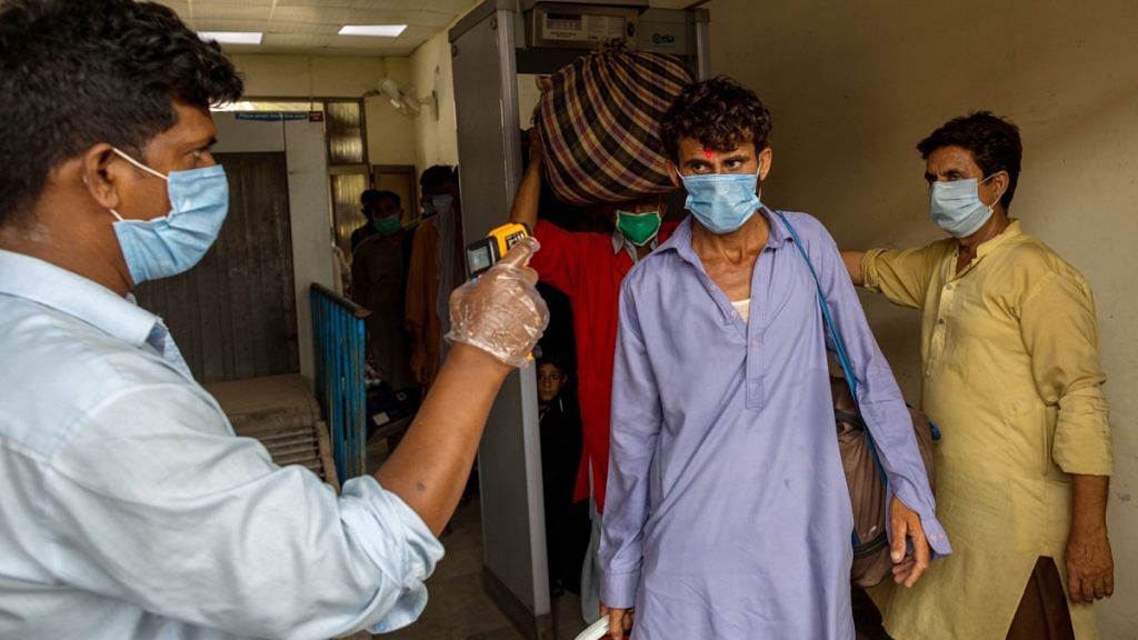 A passenger wearing a mask has his temperature checked at Karachi Cantonment railway station, in Karachi, Pakistan, on Tuesday, July 28, 2028 July 2020 Asim Hafeez | Bloomberg  