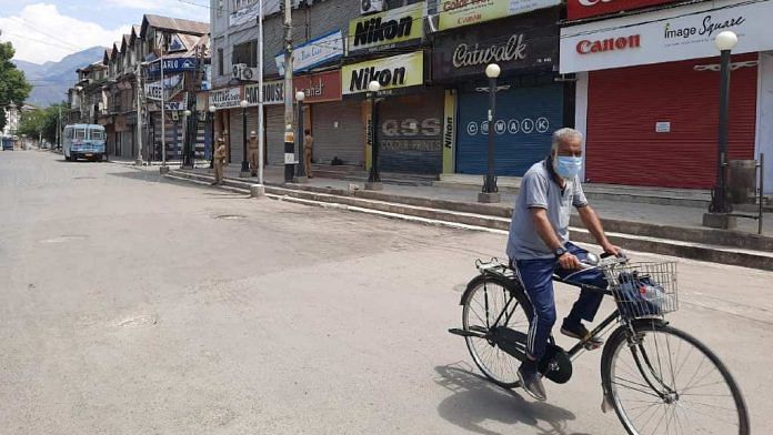 A man cycles past closed shops on a deserted road amid curfew in Srinagar Tuesday | Azaan Javaid | ThePrint