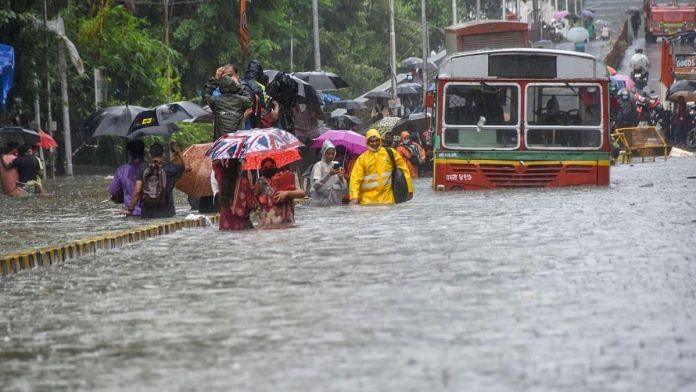 Commuters wade through a waterlogged street at Parel, following heavy rainfall, in Mumbai | PTI