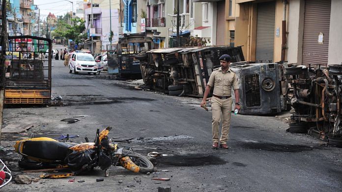 Representational image. | A police personnel marches in Devara Jeevana Halli, where an angry mob attacked and vandalised properties, in Bengaluru. | Photo: ANI