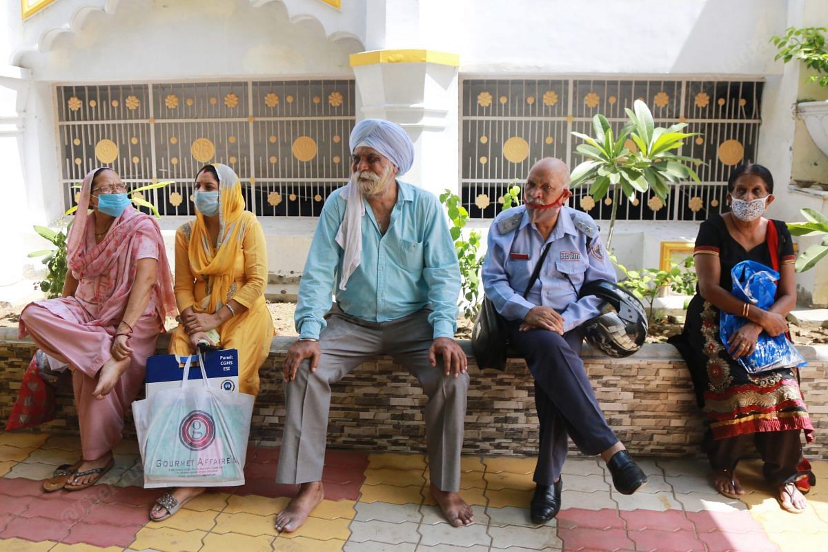 Tired people sit at the side while waiting for their turn | Photo: Manisha Mondal | ThePrint