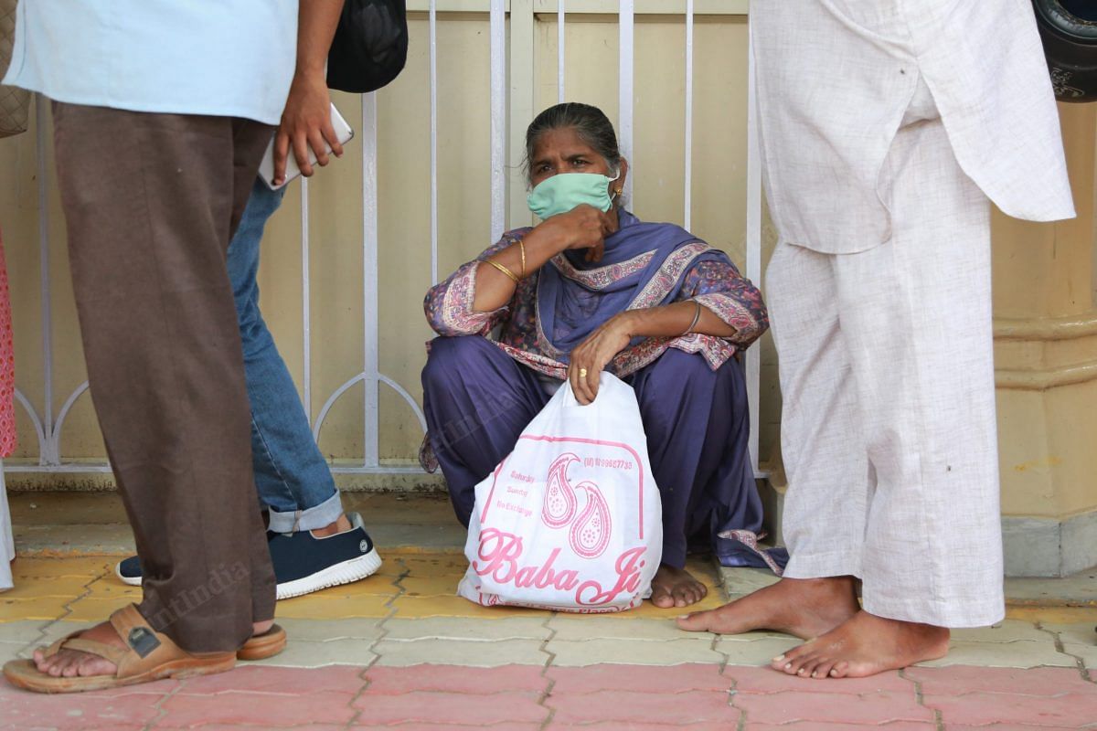 A woman sits while standing in queue | Photo: Manisha Mondal | ThePrint