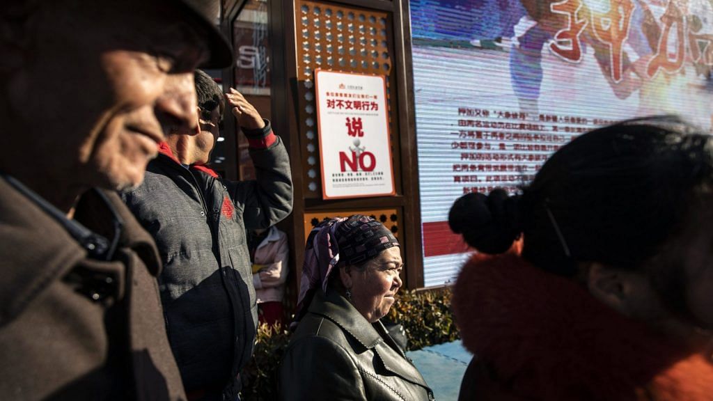 A sign warning against "uncivilized behavior" is displayed as spectators watch a street performance in the main bazaar in Urumqi, Xinjiang autonomous region, China | Bloomberg