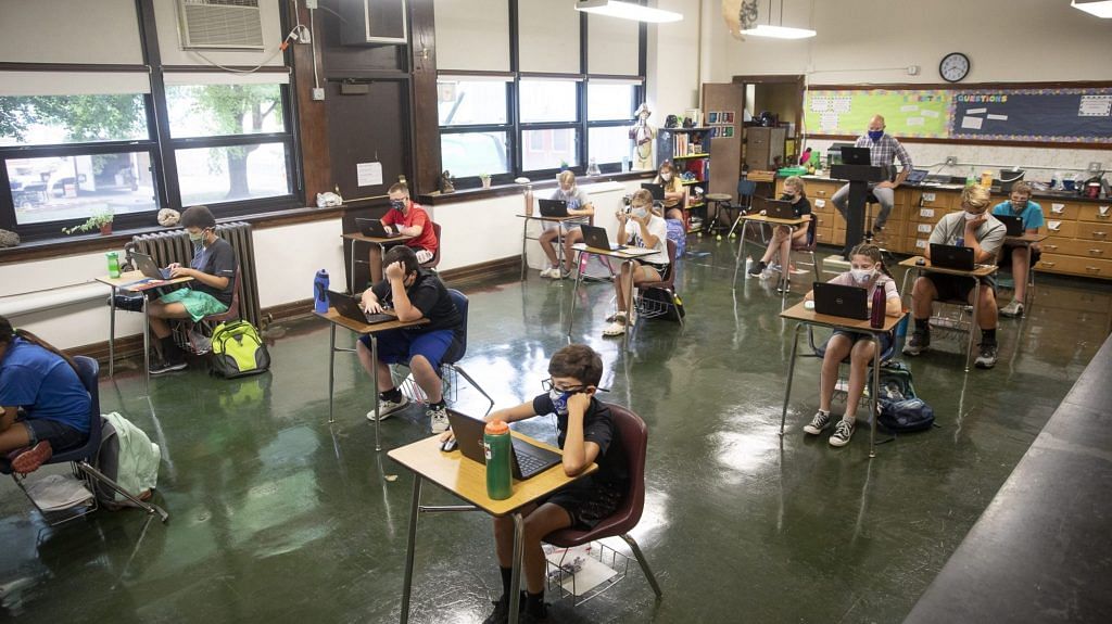 Students wearing protective masks work at their desks at a school in US | Photographer: Daniel Acker | Bloomberg