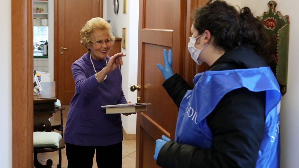 A volunteer from the Community of Sant'Egidio, speaks to an elderly woman during a home-care service during lockdown in in Rome, Italy | Photo by Marco Di Lauro | Getty Images via Bloomberg