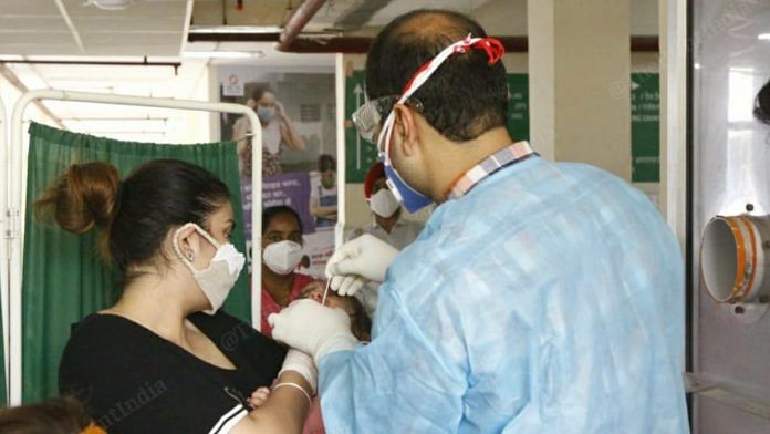 A mother holds her newborn as a doctor collects samples for a Covid-19 test at Mohali Civil Hospital in Punjab | Praveen Jain | ThePrint