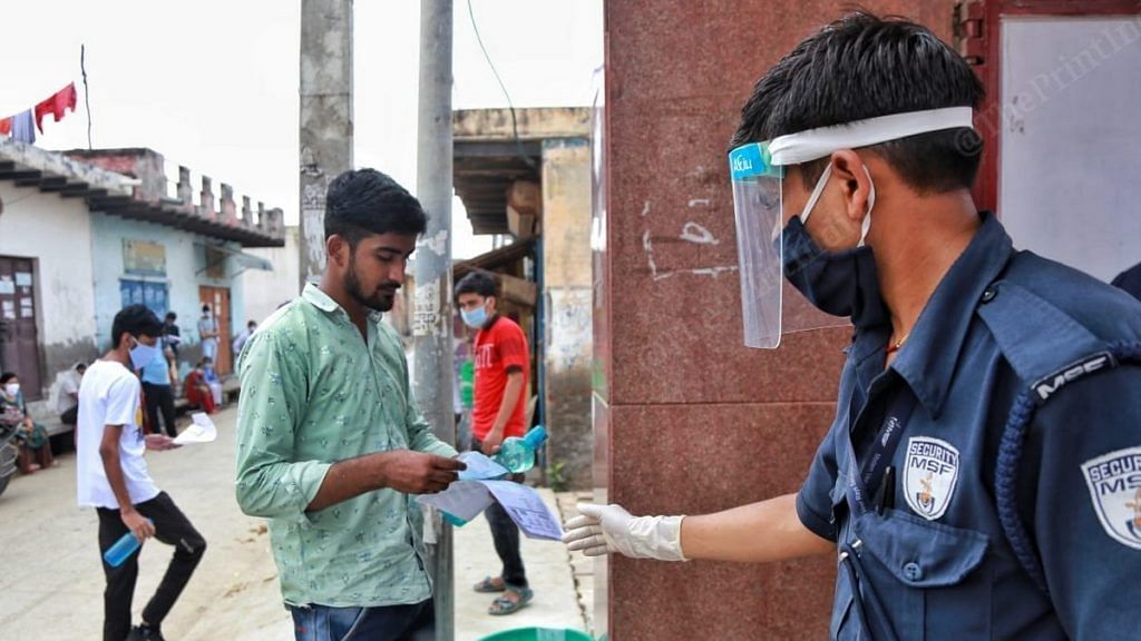 Vineet shows his credentials to the security guard outside the exam centre in Rohini | Photo: Manisha Mondal | ThePrint