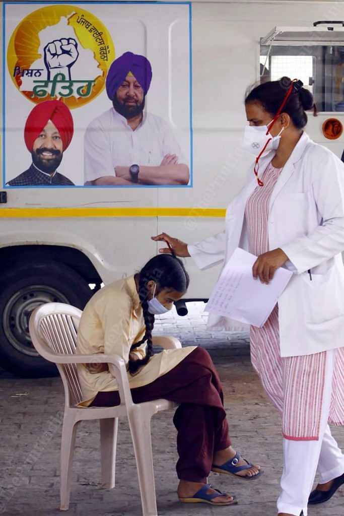 A nurse on sampling duty blessing a young girl in Bakarpur village ahead of her turn for COVID—19 testing | Praveen Jain | ThePrint