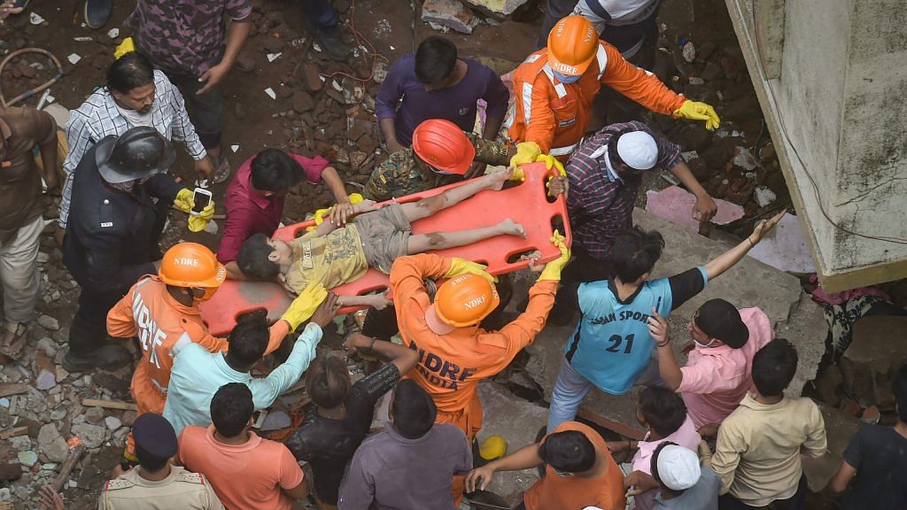 National Disaster Response Force NDRF and Fire brigade rescue an injured child after a three storey building collapsed, at Bhiwandi in Thane district, Monday | PTI