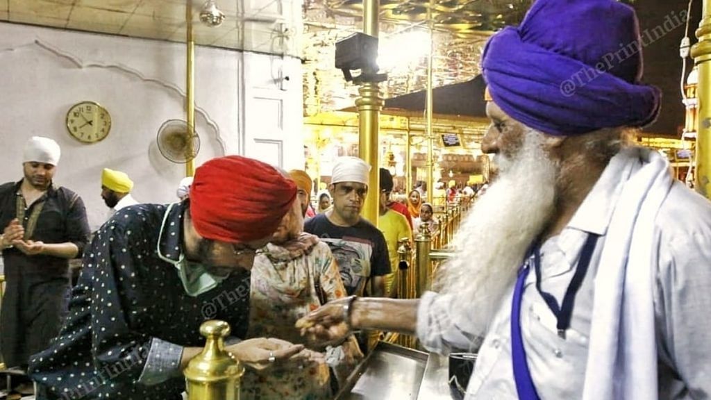 A sewadar gives prasad to a devotee at Golden Temple. None of them is wearing a mask. | Photo: Praveen Jain/ThePrint