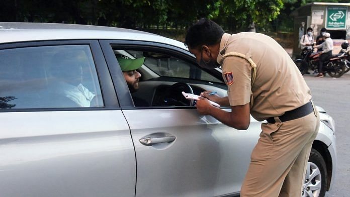 A police personnel fines an individual for violating traffic rules and not wearing a mask. | Photo: ANI