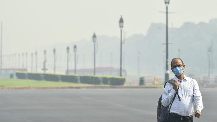 A man wearing a face mask walks on Rajpath road amid hazy weather conditions in October 2020 | PTI
